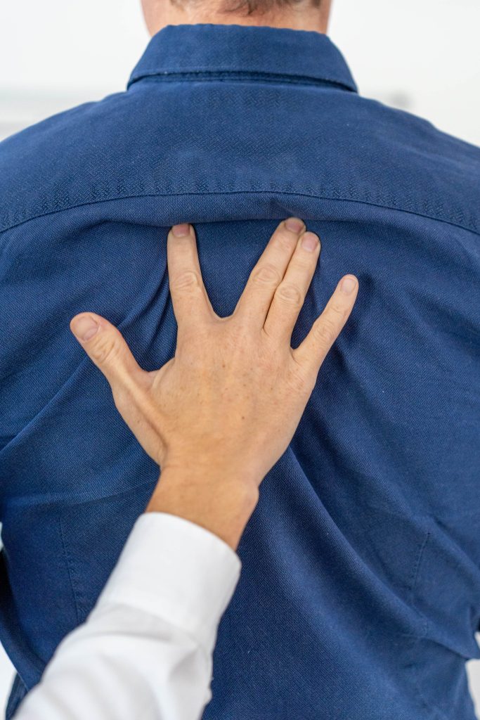 Main de Juliette Marret stimulant un point réflexe neurolymphatique postérieur sur le dos d’un volontaire