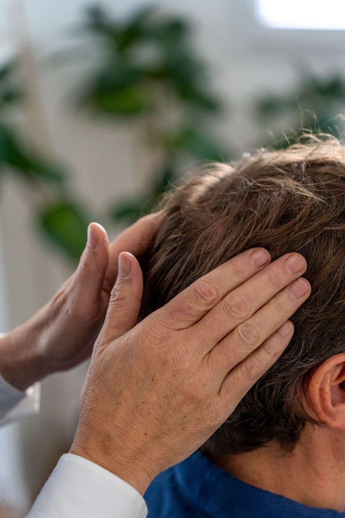 Mains de Juliette Marret posées sur les bosses pariétales d’un volontaire pour activer les points réflexes neurovasculaires
