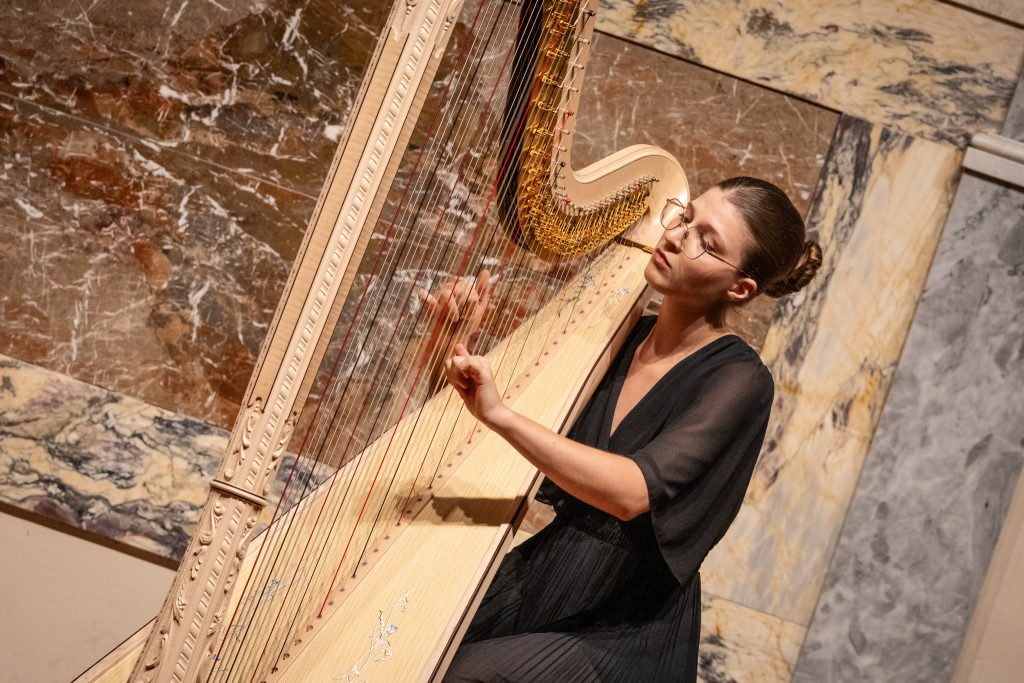 Photo d’une harpiste professionnelle jouant de la harpe, cliente régulière témoignant des bienfaits du Touch for Health